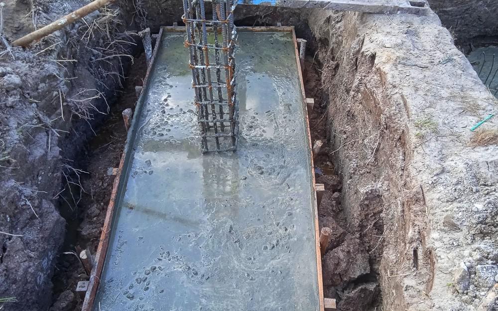 wet concrete footing just poured into footing form with rebar wet concrete footing just poured into footing form with rebar