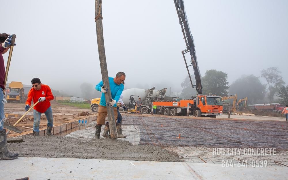 pouring wet concrete from truck on large slab with rebar reinforcement pouring wet concrete from truck on large slab with rebar reinforcement