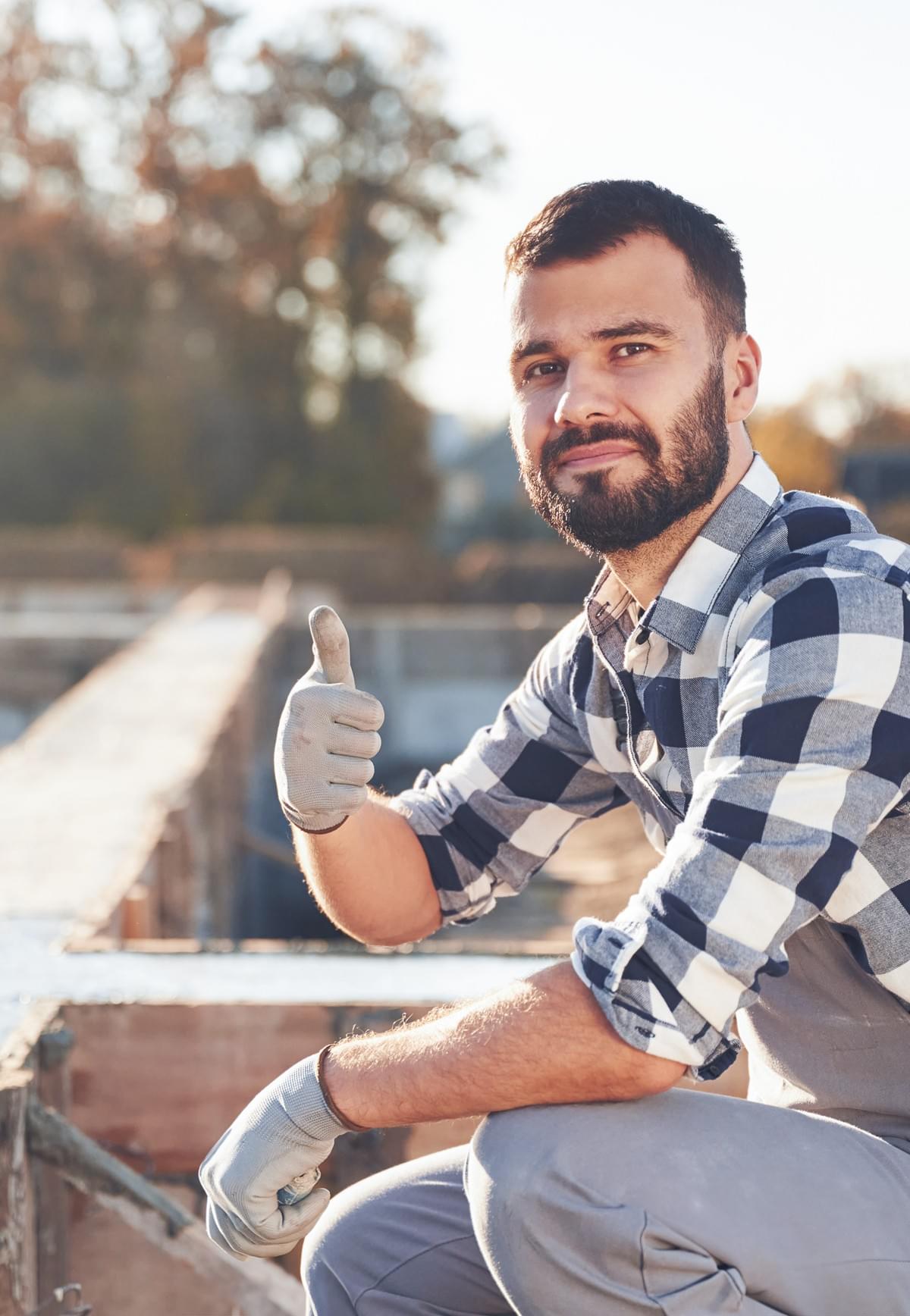 Concrete Crew member smiling and giving thumbs up at the work site of a concrete foundation build Concrete Crew member smiling and giving thumbs up at the work site of a concrete foundation build