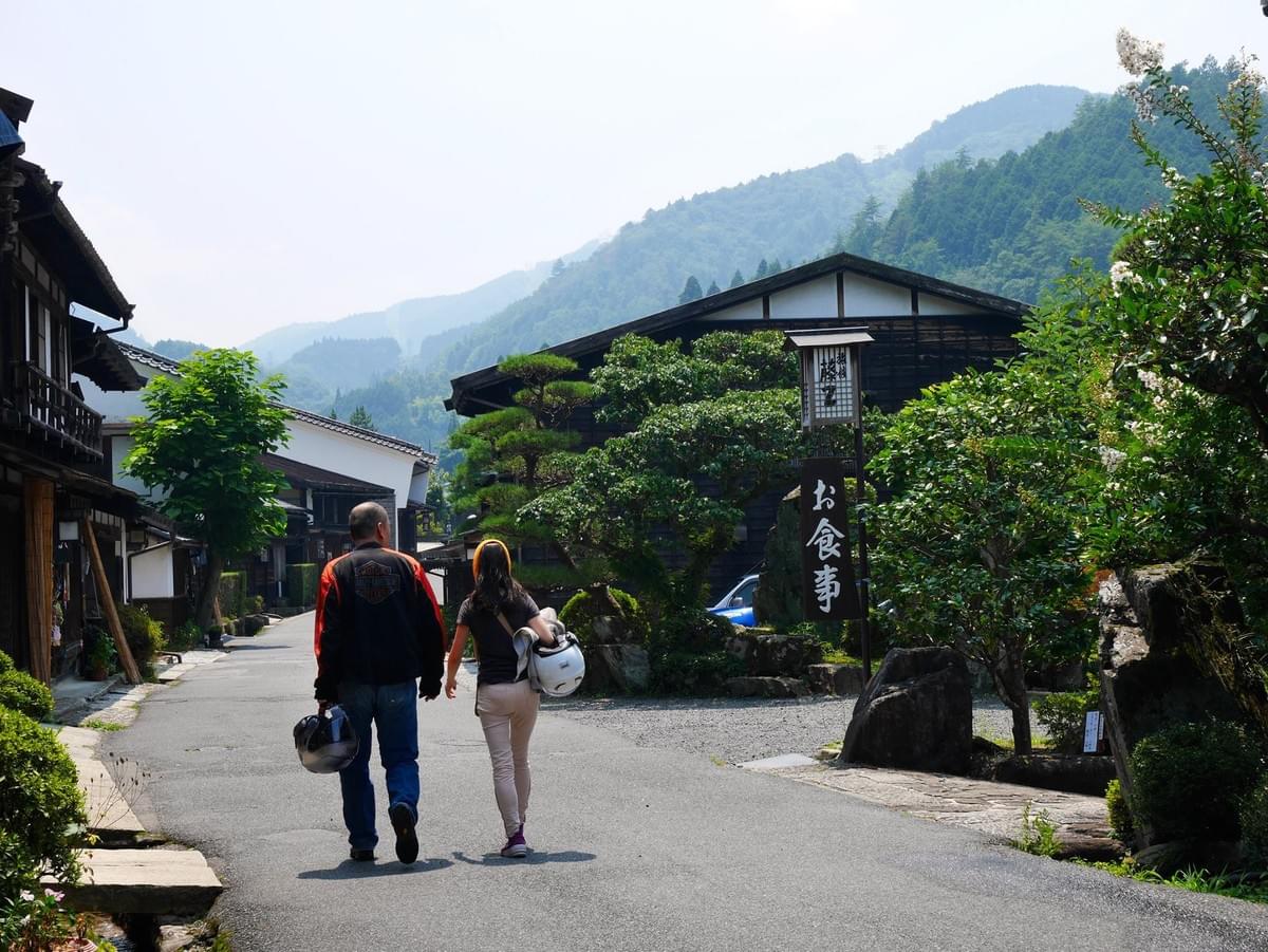 Travellers walking through a quiet rural village in Japan, an example of unhurried, immersive travel Travellers walking through a quiet rural village in Japan, an example of unhurried, immersive travel