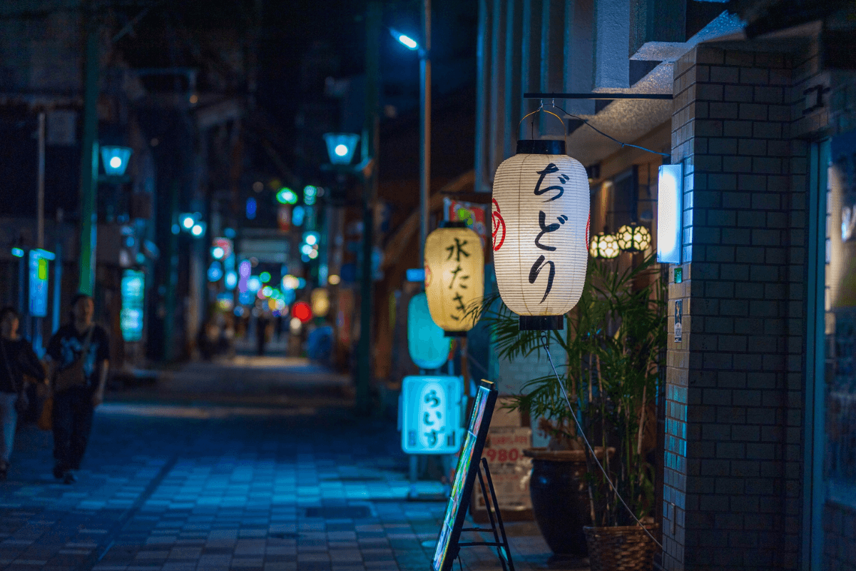 Lantern-lit Japanese street at night, representing unhurried evening life beyond tourist areas Lantern-lit Japanese street at night, representing unhurried evening life beyond tourist areas