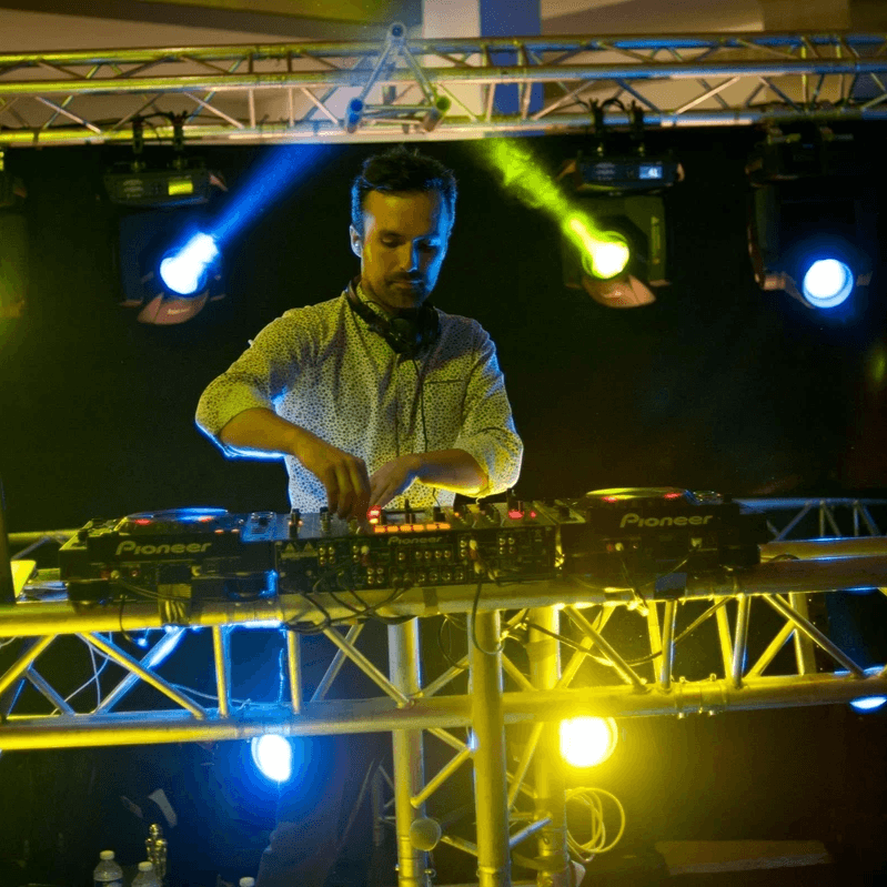 DJ en train de mixer avec plusieurs projecteurs derrière lui DJ en train de mixer avec plusieurs projecteurs derrière lui