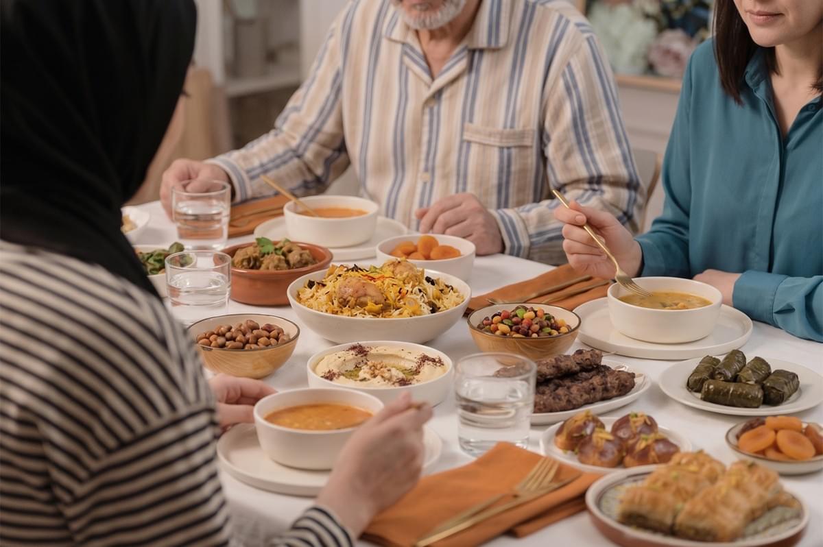 A traditional Middle Eastern dinner spread featuring chicken biryani, hummus, kebabs, and dolma shared by a family. A traditional Middle Eastern dinner spread featuring chicken biryani, hummus, kebabs, and dolma shared by a family.