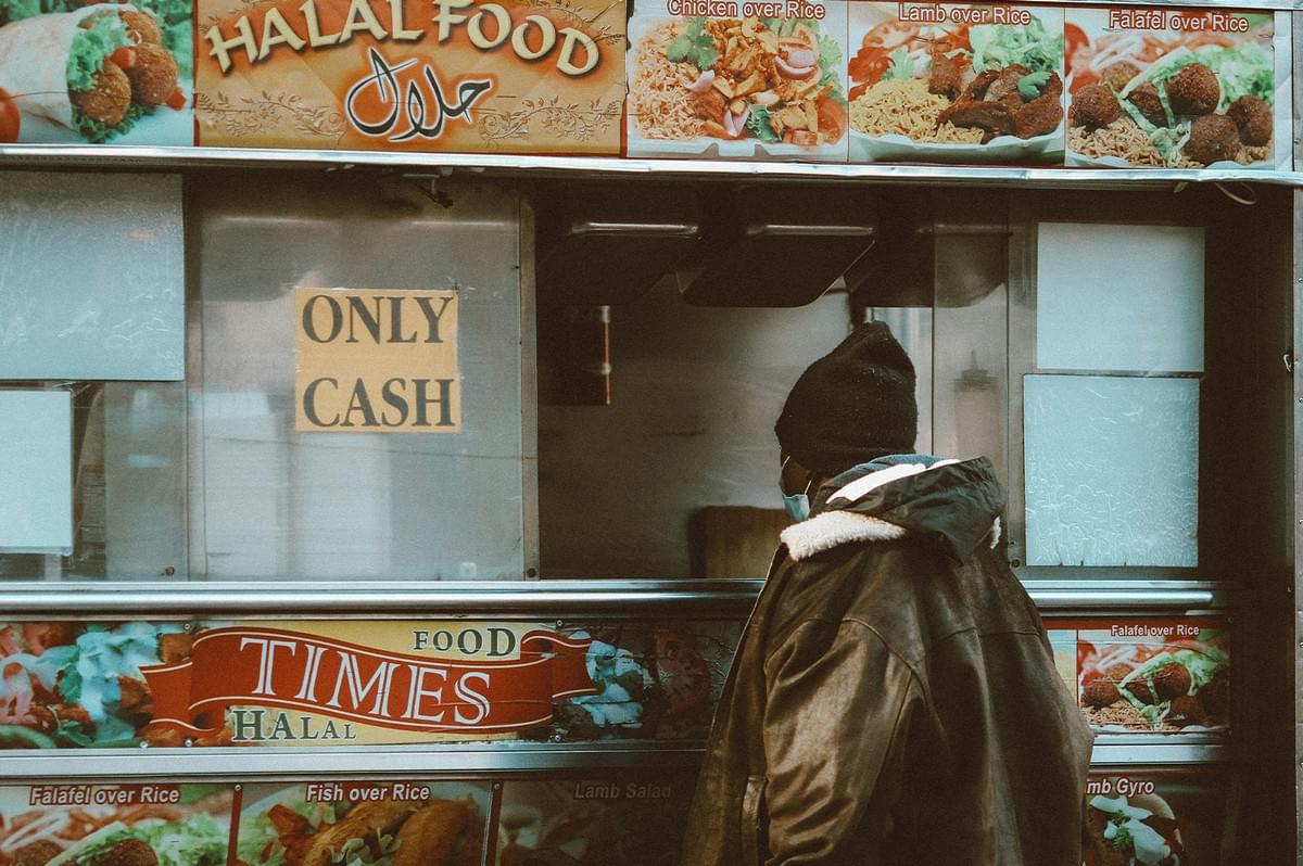 Customer in mask waiting at Times Halal Food cart window with menu photos. Customer in mask waiting at Times Halal Food cart window with menu photos.