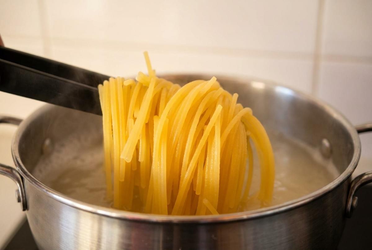 Kitchen tongs lifting cooked spaghetti pasta out of a pot of boiling water. Kitchen tongs lifting cooked spaghetti pasta out of a pot of boiling water.