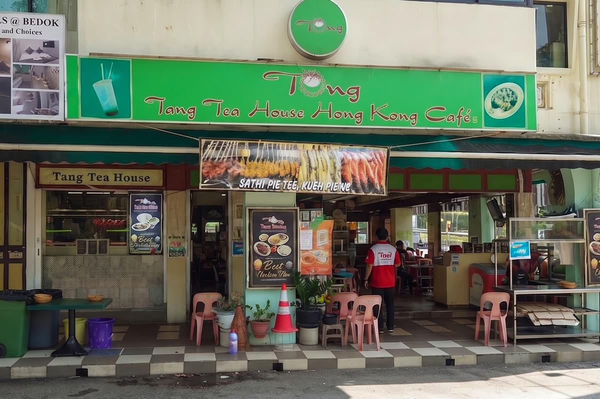 Storefront of Tang Tea House Hong Kong Café featuring a green signboard and outdoor seating. Storefront of Tang Tea House Hong Kong Café featuring a green signboard and outdoor seating.