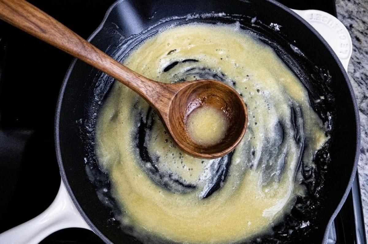 Wooden spoon stirring white roux mixture in cast iron pan Wooden spoon stirring white roux mixture in cast iron pan