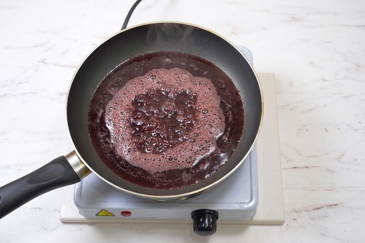 Dark red wine reduction bubbling and simmering in a non-stick pan on a portable electric burner Dark red wine reduction bubbling and simmering in a non-stick pan on a portable electric burner