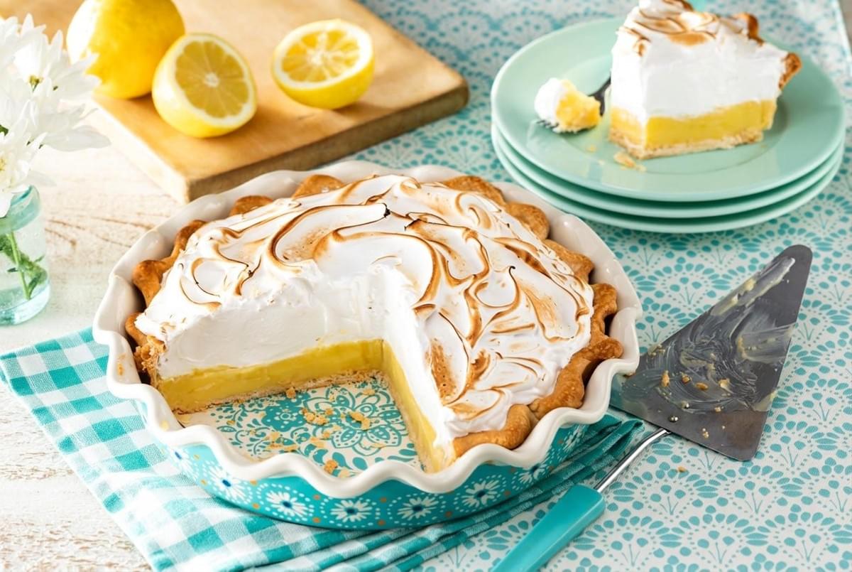 Freshly baked lemon meringue pie in a turquoise dish with one slice removed and placed on a side plate. Freshly baked lemon meringue pie in a turquoise dish with one slice removed and placed on a side plate.