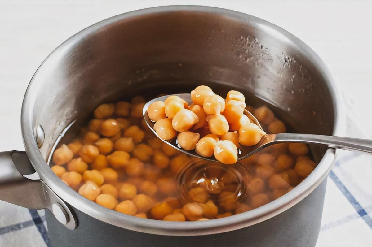 Soaked lentils in a pot with a spoon lifting a portion, showing the legumes submerged in water. Soaked lentils in a pot with a spoon lifting a portion, showing the legumes submerged in water.