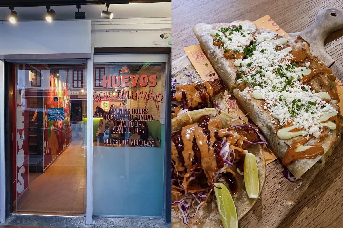 Left: An eye-level, medium shot of the storefront entry to 'Huevos The Mexican Experience', featuring a glass door, track spotlighting, a wooden floor interior pathway, and window text displaying opening hours. Right: A three-quarter, close-up food shot on a wooden board presenting two tacos drizzled with orange sauce and garnished with red cabbage and lime wedges alongside a large, folded quesadilla topped with crumbled white cotija cheese, light green crema, and chopped chives. Left: An eye-level, medium shot of the storefront entry to 'Huevos The Mexican Experience', featuring a glass door, track spotlighting, a wooden floor interior pathway, and window text displaying opening hours. Right: A three-quarter, close-up food shot on a wooden board presenting two tacos drizzled with orange sauce and garnished with red cabbage and lime wedges alongside a large, folded quesadilla topped with crumbled white cotija cheese, light green crema, and chopped chives.