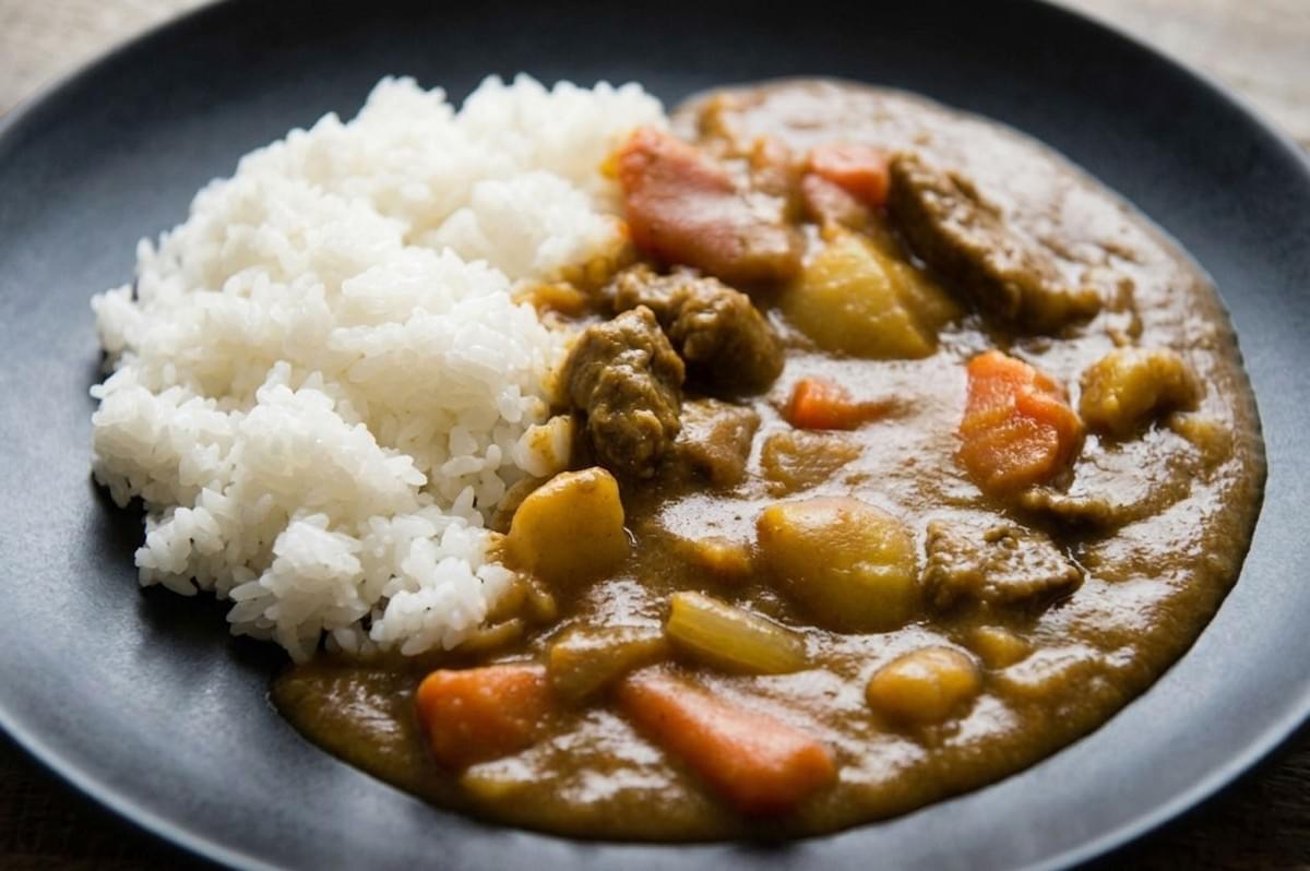 Plate of Kare Raisu featuring fluffy white rice alongside thick brown curry sauce with meat and vegetables Plate of Kare Raisu featuring fluffy white rice alongside thick brown curry sauce with meat and vegetables