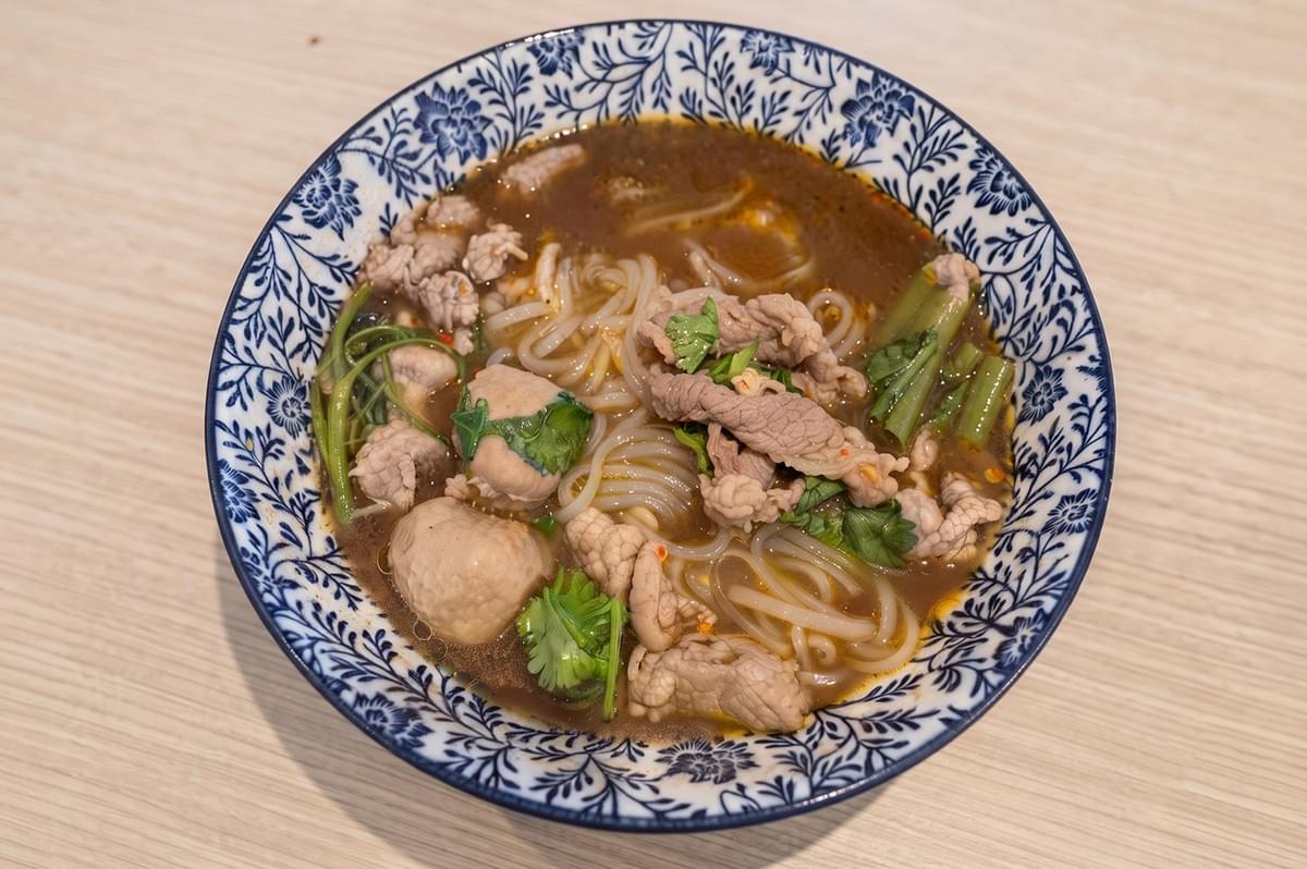 A bowl of authentic Halal Thai Beef Boat Noodles with beef slices, meatballs, and noodles served in a patterned bowl. A bowl of authentic Halal Thai Beef Boat Noodles with beef slices, meatballs, and noodles served in a patterned bowl.