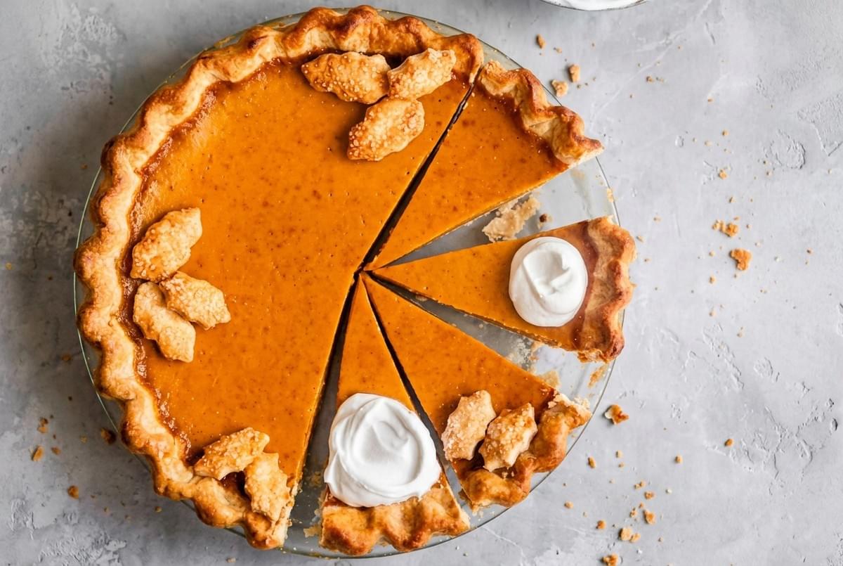 Golden coconut tart on a floral pattern plate with a pie server lifting one slice on a checkered tablecloth. Golden coconut tart on a floral pattern plate with a pie server lifting one slice on a checkered tablecloth.