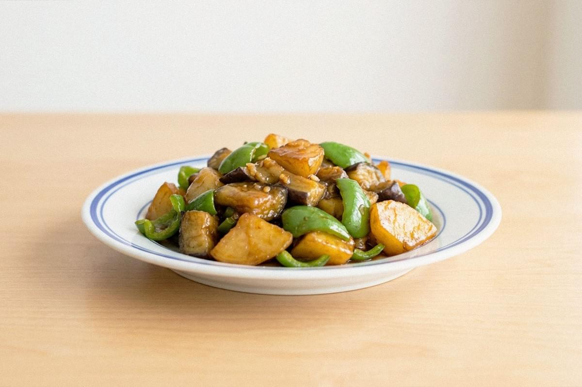 Plate of stir-fried potatoes, green peppers, and mushrooms in a glossy savory sauce. Plate of stir-fried potatoes, green peppers, and mushrooms in a glossy savory sauce.