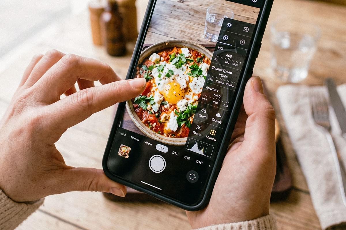 A smartphone camera in manual mode capturing a dish topped with eggs, herbs, and sauce. A smartphone camera in manual mode capturing a dish topped with eggs, herbs, and sauce.
