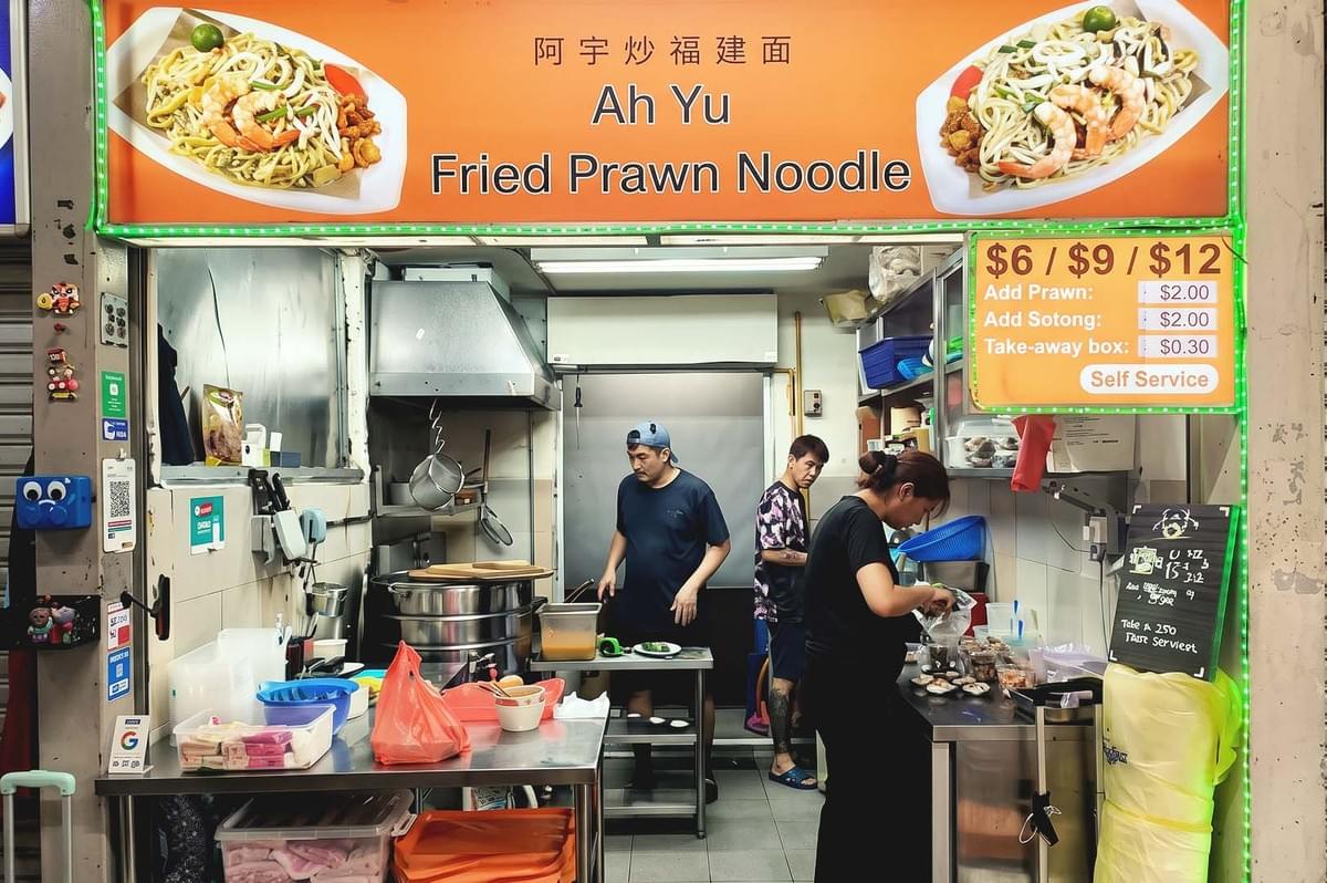 Storefront with orange banner of Ah Yu Fried Prawn Noodle with two noodles served on white plate photos on the side Storefront with orange banner of Ah Yu Fried Prawn Noodle with two noodles served on white plate photos on the side