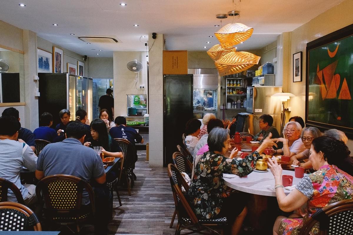 Simple and straightforward Hup Lok interior with elders and young adults dining in warm ambient lighting Simple and straightforward Hup Lok interior with elders and young adults dining in warm ambient lighting