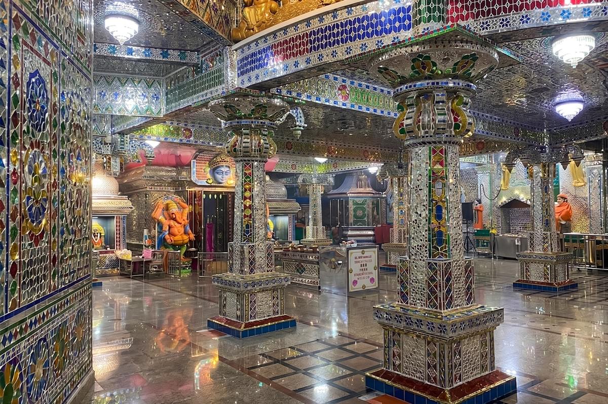 Arulmigu Sri Rajakaliamman Glass Temple interior featuring pillars and walls covered in colorful mosaic glass artwork with Hindu deities. Arulmigu Sri Rajakaliamman Glass Temple interior featuring pillars and walls covered in colorful mosaic glass artwork with Hindu deities.