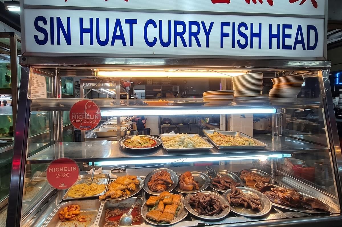 Food display case at Sin Huat Curry Fish Head featuring various dishes and 2020 Michelin Guide recognition stickers. Food display case at Sin Huat Curry Fish Head featuring various dishes and 2020 Michelin Guide recognition stickers.