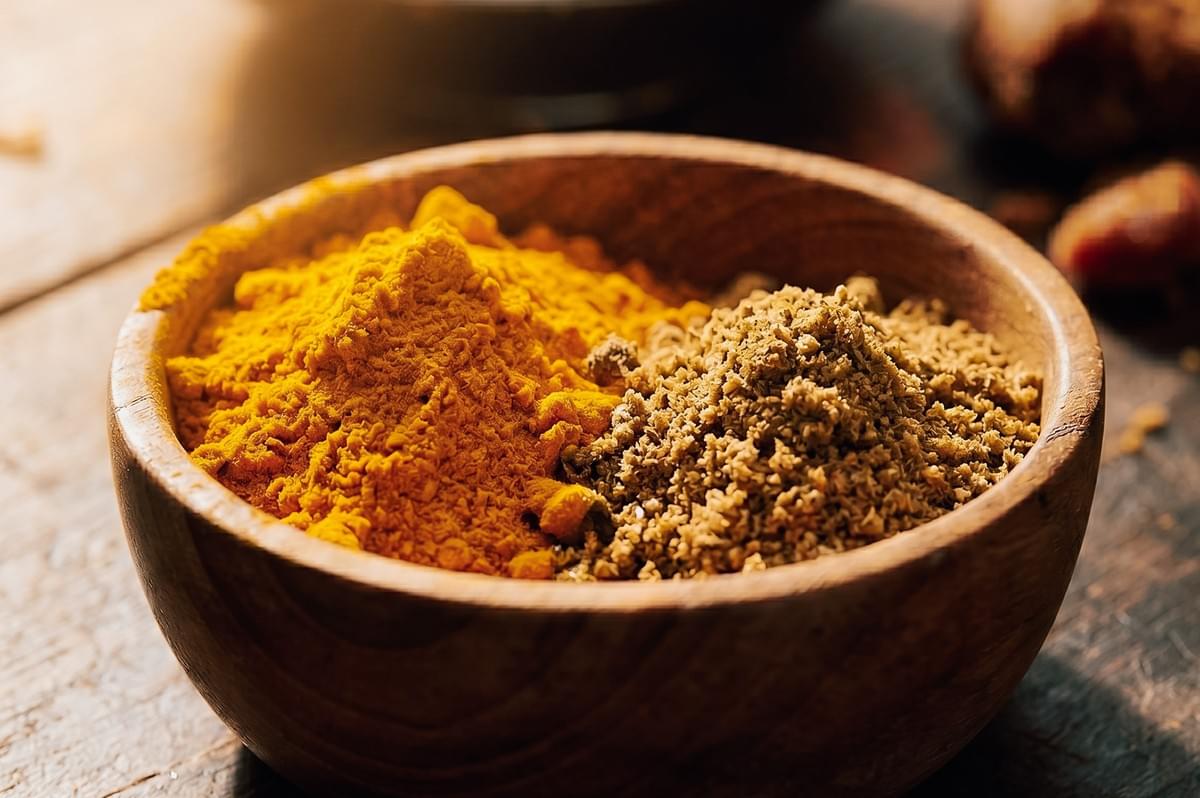 Macro close-up shot of turmeric powder and coriander spice blend in a wooden bowl for Indonesian satay marinade preparation Macro close-up shot of turmeric powder and coriander spice blend in a wooden bowl for Indonesian satay marinade preparation