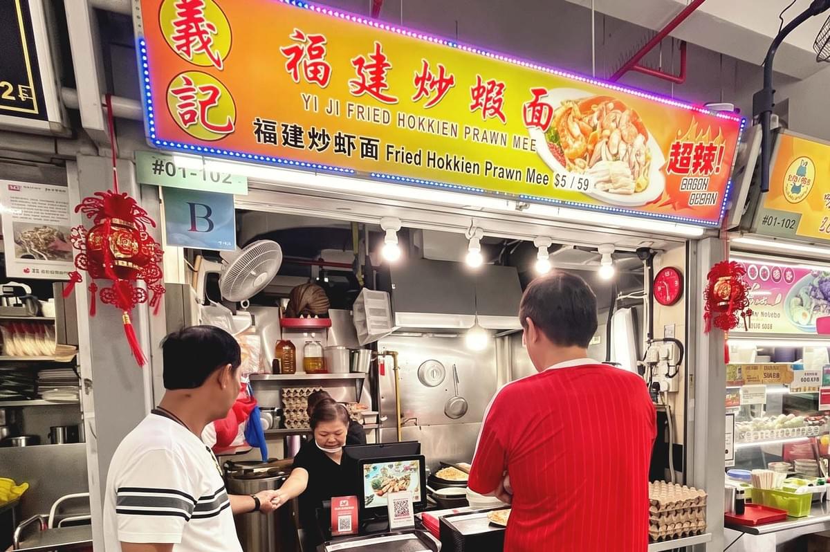 Storefront with yellow orange gradient signage of Yi Ji Fried Hokkien Prawn Mee with red chinese characters Storefront with yellow orange gradient signage of Yi Ji Fried Hokkien Prawn Mee with red chinese characters