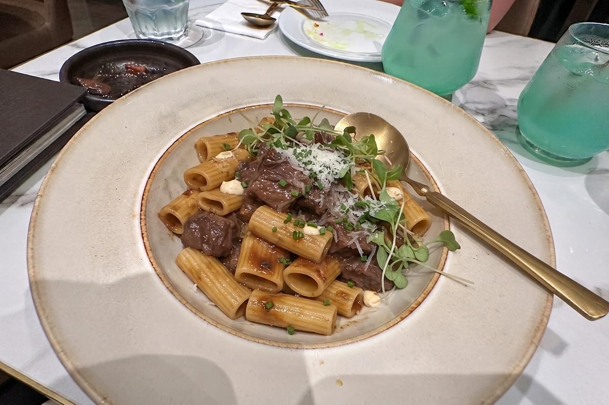 Wagyu Beef Cheeks with Lemak Chilli Padi rigatoni pasta served in a fine dining bowl with grated cheese and microgreens. Wagyu Beef Cheeks with Lemak Chilli Padi rigatoni pasta served in a fine dining bowl with grated cheese and microgreens.