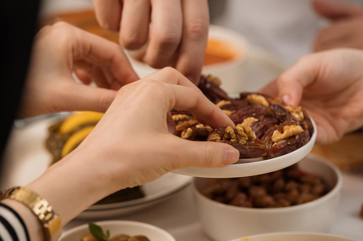 Friends sharing halal food and dates together at a dining table. Friends sharing halal food and dates together at a dining table.