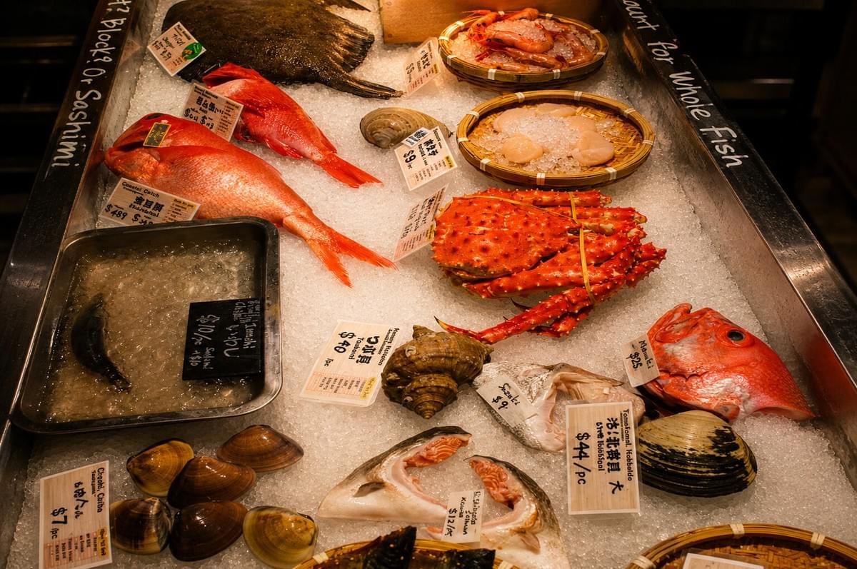 Fresh seafood display on crushed ice featuring whole red snapper, king crab, scallops, and clams. Fresh seafood display on crushed ice featuring whole red snapper, king crab, scallops, and clams.