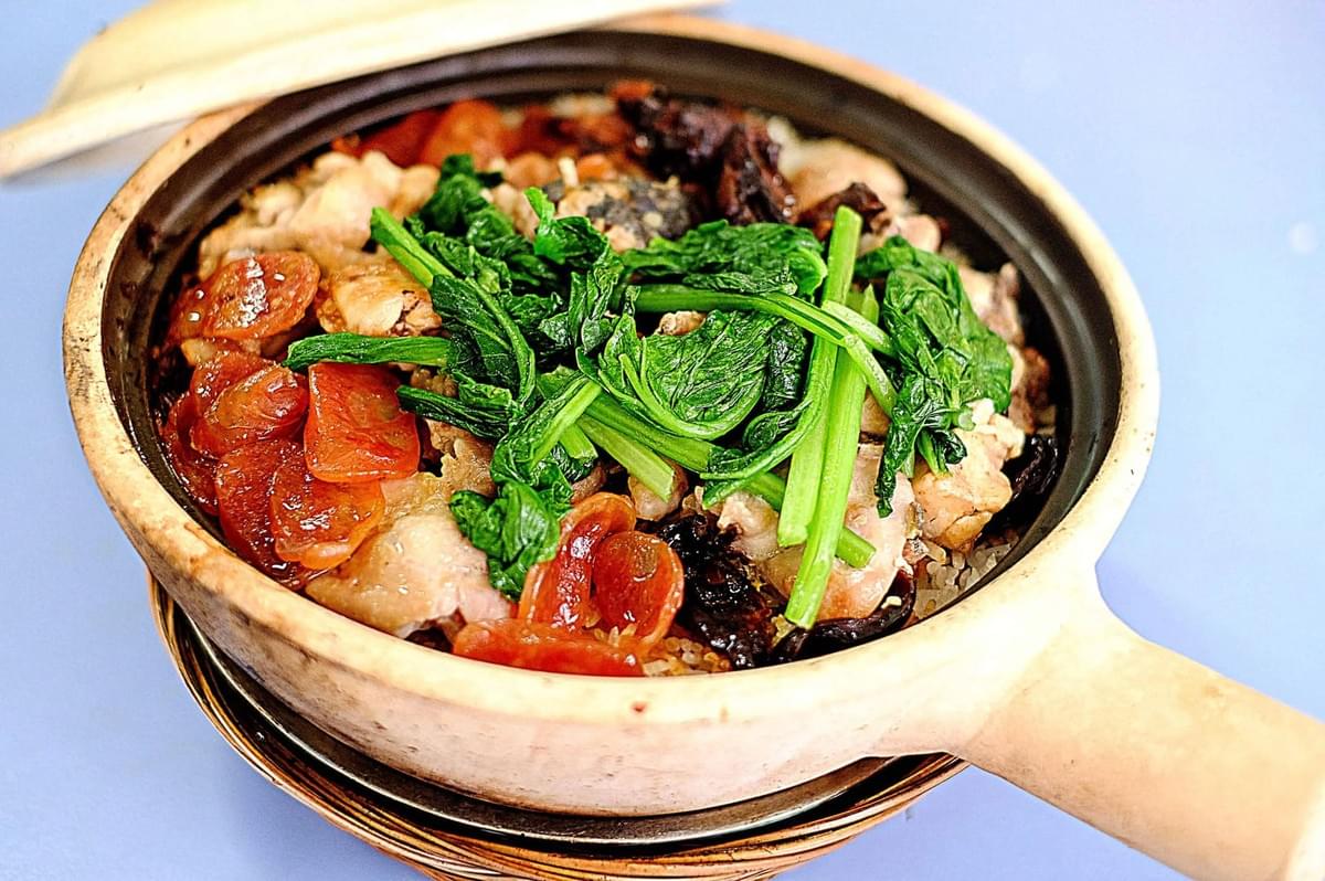 A bowl of Claypot Chicken Rice, a popular dish from Singapore, featuring rice, chicken, and vegetables. A bowl of Claypot Chicken Rice, a popular dish from Singapore, featuring rice, chicken, and vegetables.