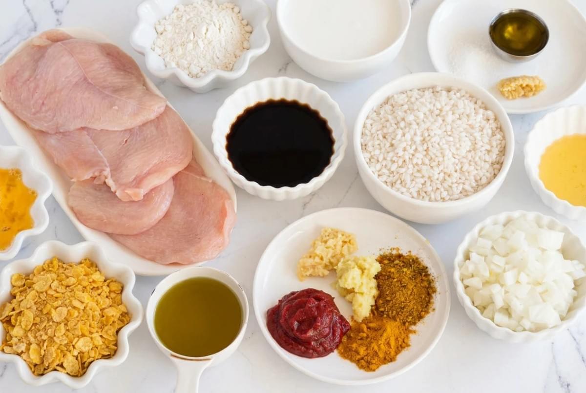 Flat-lay arrangement of ingredients for Japanese curry, including raw chicken, rice, soy sauce, and spices. Flat-lay arrangement of ingredients for Japanese curry, including raw chicken, rice, soy sauce, and spices.