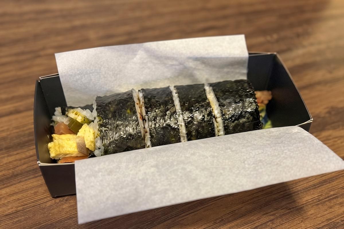 Custom Maki-San sushi roll filled with rice, egg, and fillings served in a black box for a quick takeaway lunch. Custom Maki-San sushi roll filled with rice, egg, and fillings served in a black box for a quick takeaway lunch.
