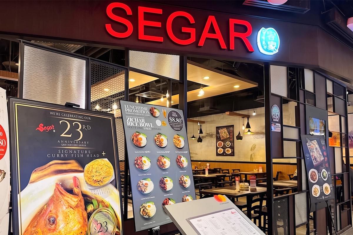 Segar restaurant storefront with promotional signs for signature curry fish head and zi-char rice bowls. Segar restaurant storefront with promotional signs for signature curry fish head and zi-char rice bowls.