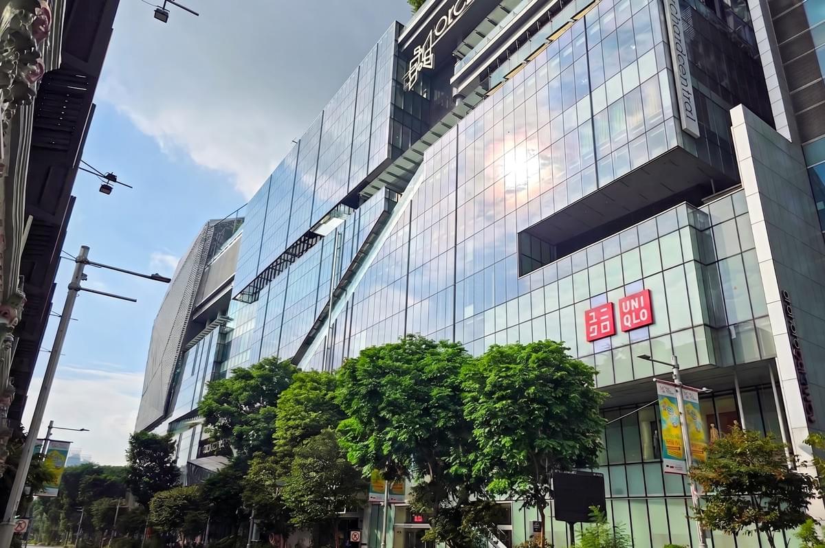 An impressive, modern glass-facade building of the Orchard Central shopping mall on Orchard Road in Singapore, featuring a prominent Uniqlo storefront and logo against a blue sky with green trees in the foreground. An impressive, modern glass-facade building of the Orchard Central shopping mall on Orchard Road in Singapore, featuring a prominent Uniqlo storefront and logo against a blue sky with green trees in the foreground.