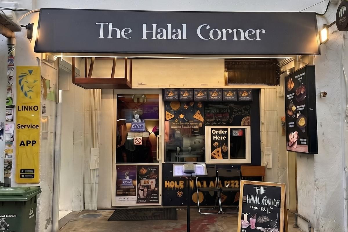 The Halal Corner restaurant storefront featuring a black signboard, order window, and menu displays. The Halal Corner restaurant storefront featuring a black signboard, order window, and menu displays.