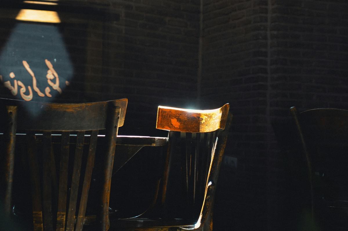 Empty wooden chairs and tables inside a cozy restaurant with soft lighting. Empty wooden chairs and tables inside a cozy restaurant with soft lighting.