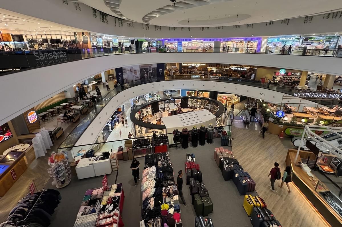 Interior view of a multi-level shopping mall in Singapore featuring a circular atrium, various retail stores, and a luggage display area. Interior view of a multi-level shopping mall in Singapore featuring a circular atrium, various retail stores, and a luggage display area.
