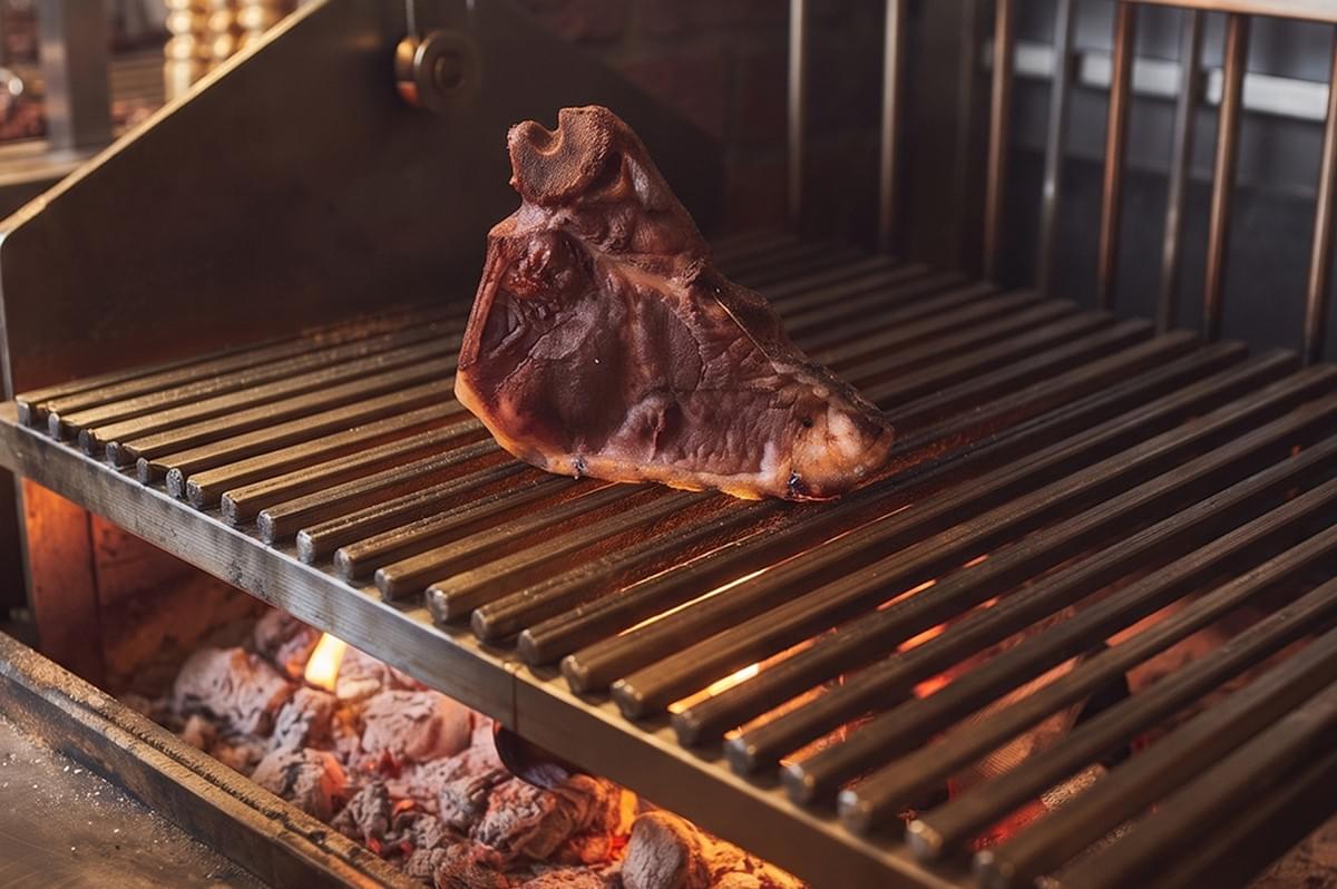 Oud Restaurant fire-grilled meat cooking over open wood fire. Oud Restaurant fire-grilled meat cooking over open wood fire.