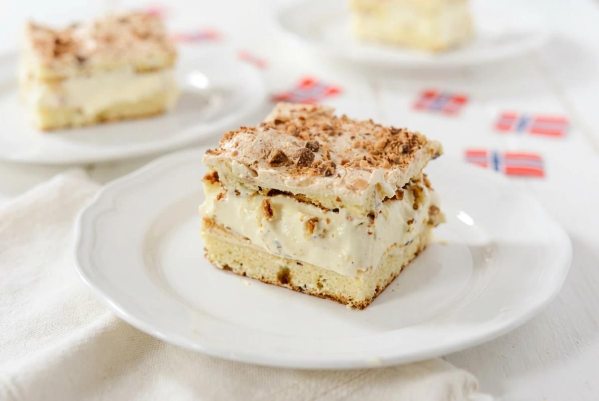 Square slice of Norwegian world's best cake (Kvæfjordkake) served on a white plate. Square slice of Norwegian world's best cake (Kvæfjordkake) served on a white plate.