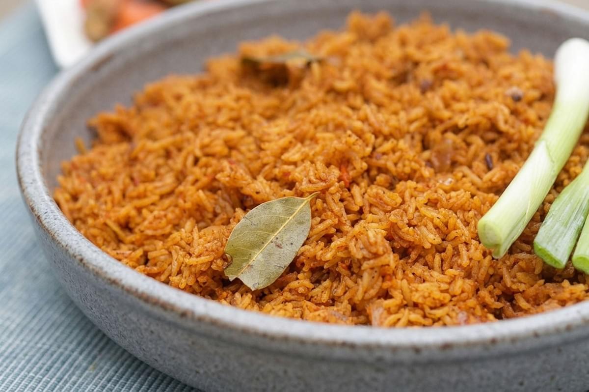 Close-up of a bowl of Ghanaian Jollof rice garnished with a bay leaf and green onions Close-up of a bowl of Ghanaian Jollof rice garnished with a bay leaf and green onions