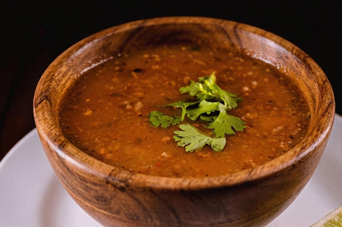 A close-up of a rustic wooden bowl filled with warm lentil soup garnished with fresh cilantro. A close-up of a rustic wooden bowl filled with warm lentil soup garnished with fresh cilantro.