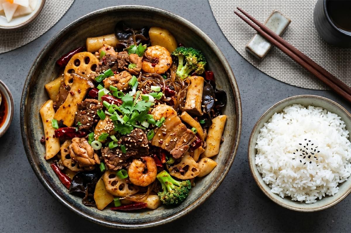 Mala xiang guo spicy stir-fry dish served with a bowl of steamed white rice. Mala xiang guo spicy stir-fry dish served with a bowl of steamed white rice.