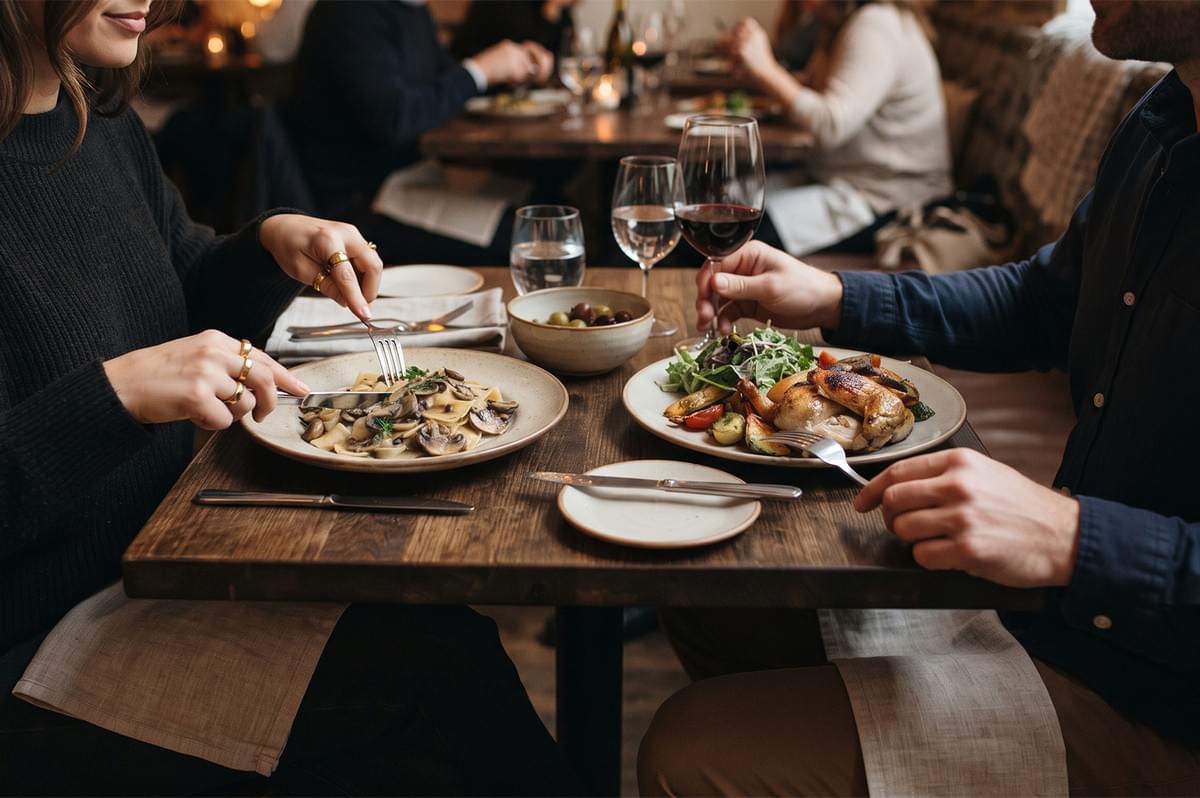 A couple enjoying a dinner date with mushroom pasta, roasted chicken, and red wine in a rustic restaurant. A couple enjoying a dinner date with mushroom pasta, roasted chicken, and red wine in a rustic restaurant.