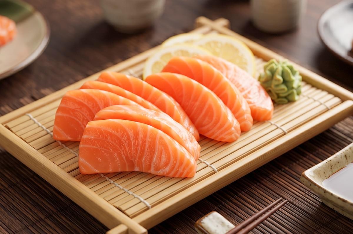 Fresh halal salmon sashimi served with lemon and wasabi on a wooden tray at The Ramen Stall in Singapore. Fresh halal salmon sashimi served with lemon and wasabi on a wooden tray at The Ramen Stall in Singapore.