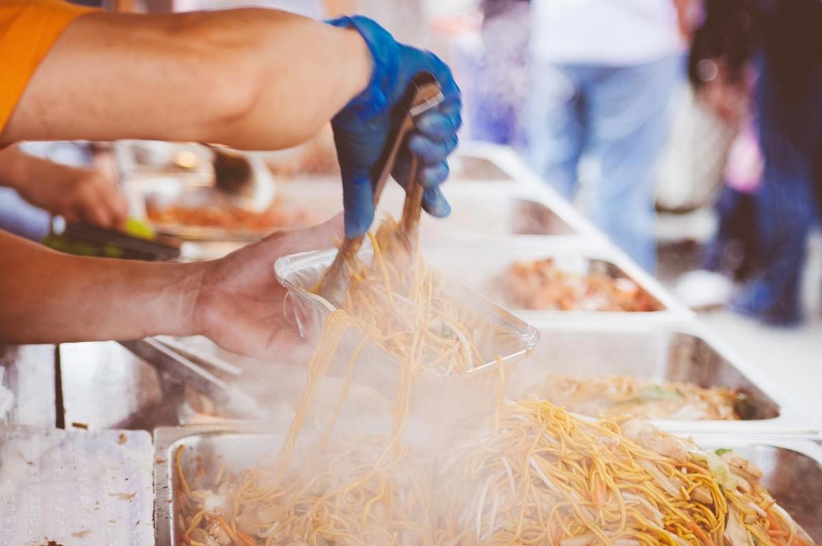Street food vendor putting noodles on container Street food vendor putting noodles on container