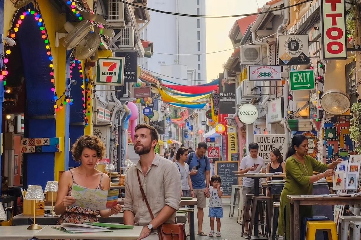 Tourists sitting at a cafe table with a map in the vibrant, narrow alleyway of Haji Lane, Singapore. Tourists sitting at a cafe table with a map in the vibrant, narrow alleyway of Haji Lane, Singapore.