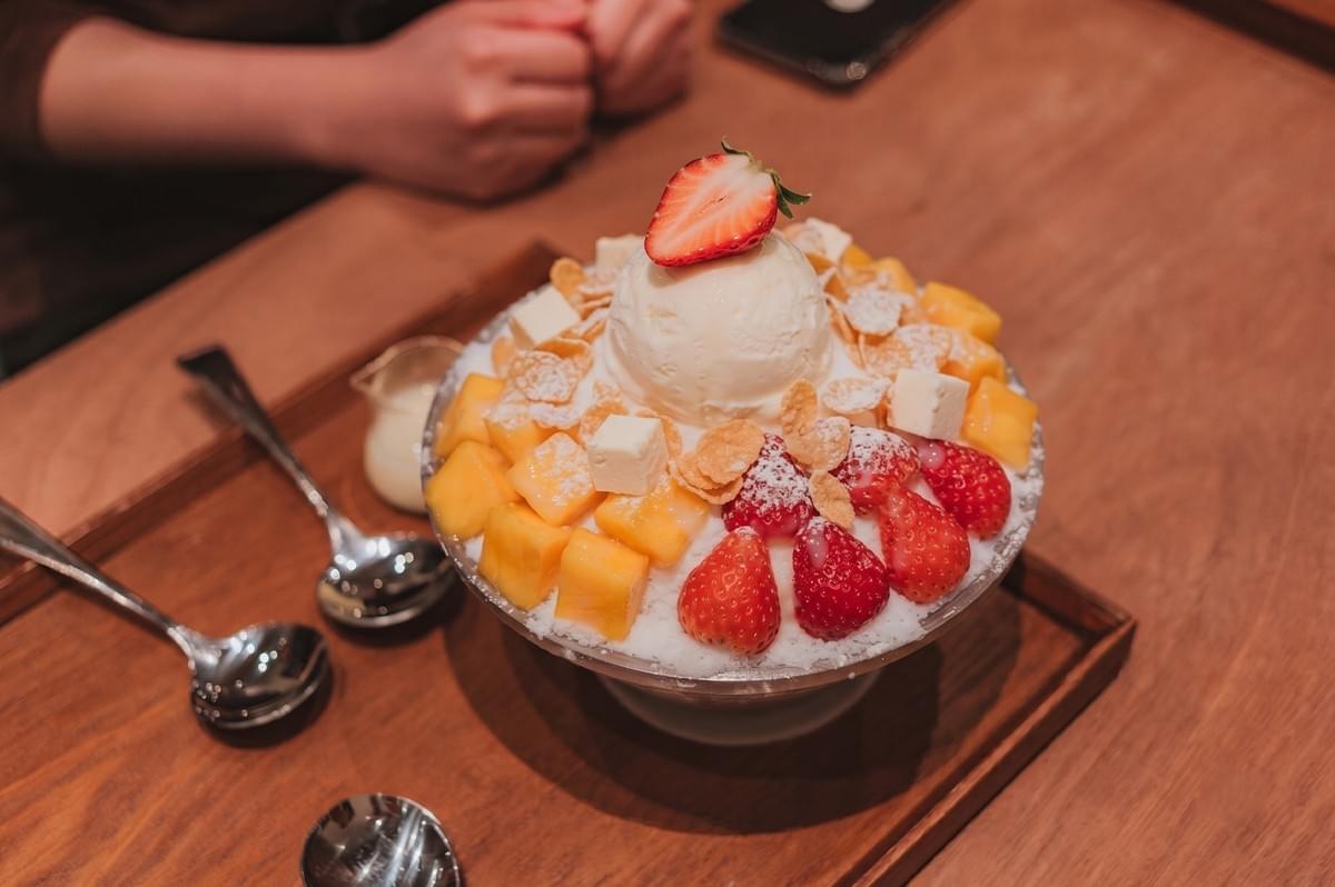 Korean bingsu topped with fresh mango, strawberries, ice cream, and cheese cubes served in a bowl. Korean bingsu topped with fresh mango, strawberries, ice cream, and cheese cubes served in a bowl.