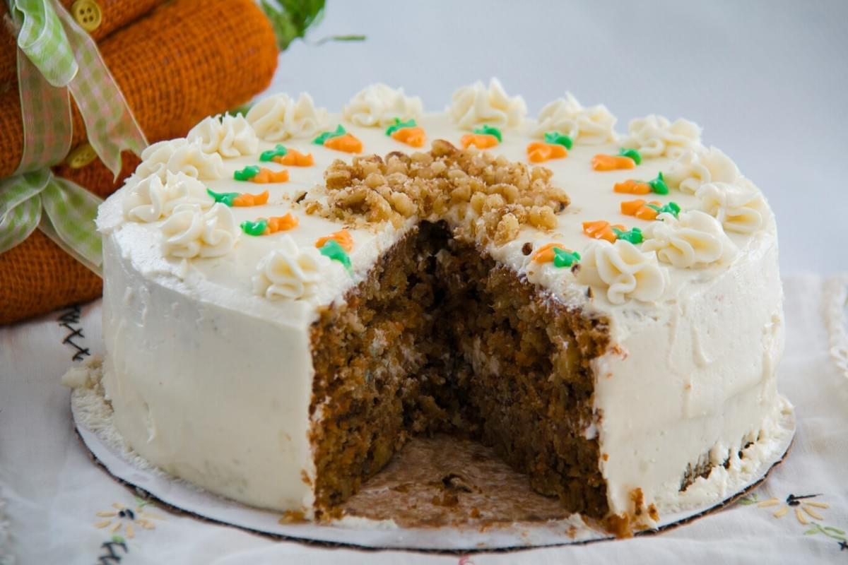 A moist carrot cake layered with creamy frosting, topped with grated carrot and nuts, offering a balance of warmth, sweetness, and texture. A moist carrot cake layered with creamy frosting, topped with grated carrot and nuts, offering a balance of warmth, sweetness, and texture.