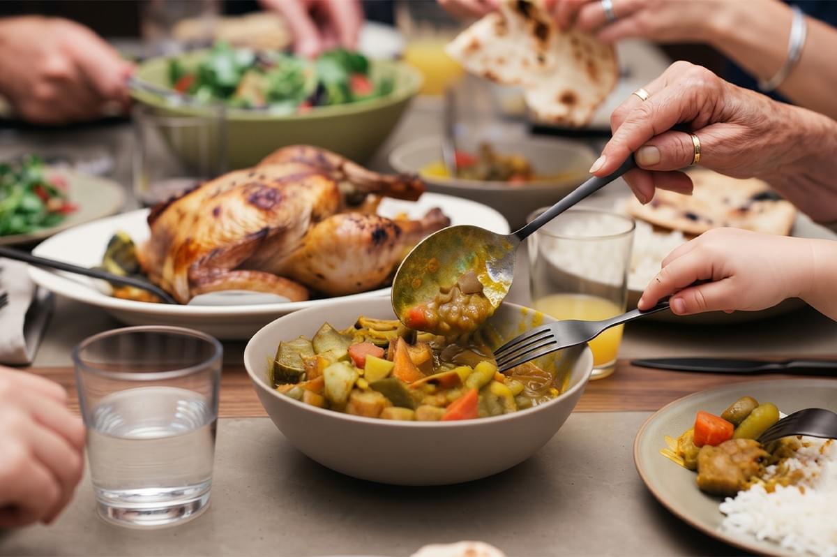 Family dining at a table sharing a feast of roasted chicken, vegetable curry, rice, and naan bread. Family dining at a table sharing a feast of roasted chicken, vegetable curry, rice, and naan bread.