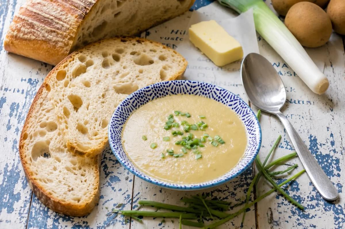 A bowl of creamy potato and leek or celeriac soup served with sliced sourdough bread and butter. A bowl of creamy potato and leek or celeriac soup served with sliced sourdough bread and butter.